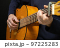 Guitarist playing acoustic guitar on black background, selective focus. 97225283