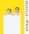 Girls sisters holding white empy poster and smiling. 97225299