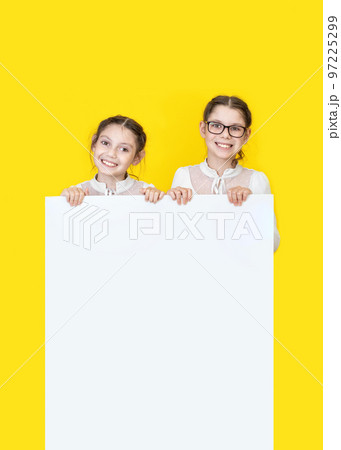 Girls sisters holding white empy poster and smiling. Girls sisters holding white empy poster and smiling. 97225299