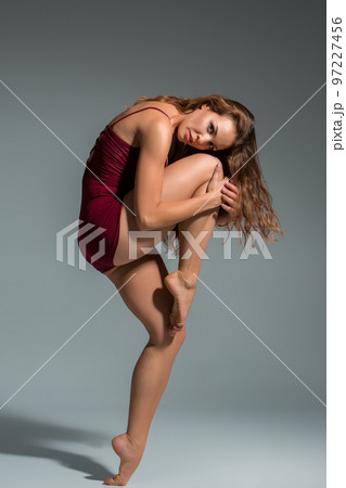 Beautiful woman dancer wearing maroon swimsuit posing on a grey studio background 97227456