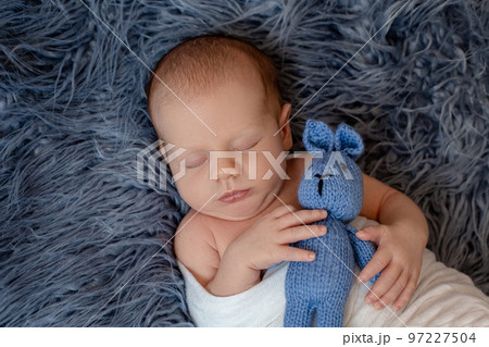 Newborn baby boy in bed. New born child sleeping under a white knitted blanket. Children sleep. 97227504