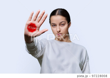 Serious teenage girl looking at camera making stop gesture with her palm 97228008