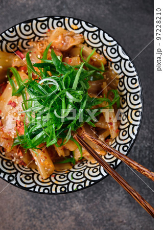 Korean traditional fermented appetizer kimchi cabbage salad in ceramic bowl with shopsticks on dark background. Top view Korean traditional fermented appetizer kimchi cabbage salad in ceramic bowl with shopsticks on dark background. Top view 97228210