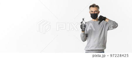 Concept of coronavirus, lifestyle and quarantine. Portrait of middle-aged man in medical mask and gloves do not recommend antiseptic, showing hand sanitizer and thumbs-down, white background Concept of coronavirus, lifestyle and quarantine. Portrait of middle-aged man in medical mask and gloves do not recommend antiseptic, showing hand sanitizer and thumbs-down, white background 97228425