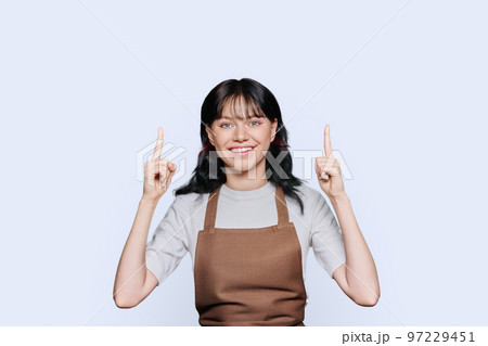 Young woman in apron showing hands up, to empty space for your advertisement 97229451