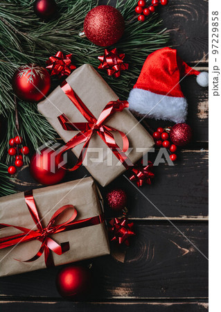 Christmass background gift boxes,red christmas tree toys,Santa hatn and spruce brance on wooden background. 97229858