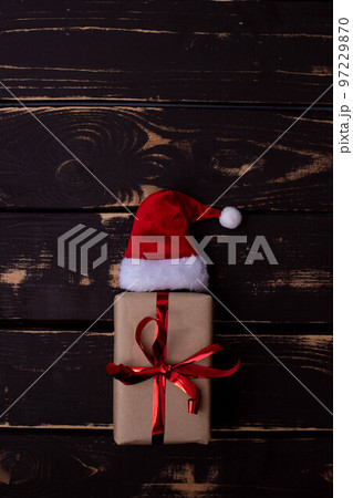 Christmass flatlay gift box and Santa hat on wooden background. Christmass flatlay gift box and Santa hat on wooden background. 97229870