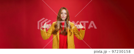 Self-assured assertive and optimsitic charming female entrepreneur with ginger hair in yellow coat pointing at herself proudly brag own success or willing to be candidate smiling confident 97230158