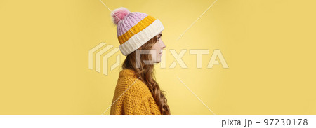 Profile shot attractive female curly hairstyle wearing hat knitted sweater standing queue order hot warm drink look left normal casual expression, posing yellow background studio Profile shot attractive female curly hairstyle wearing hat knitted sweater standing queue order hot warm drink look left normal casual expression, posing yellow background studio 97230178
