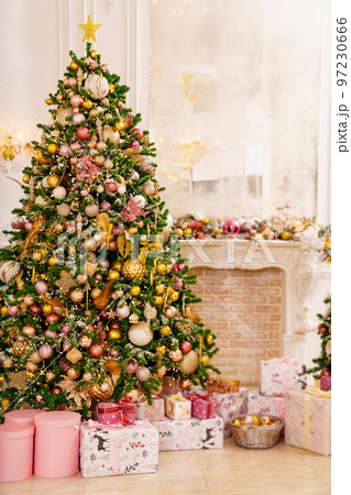 A large beautiful traditional Christmas tree with gifts in a classic interior. A large beautiful traditional Christmas tree with gifts in a classic interior. 97230666