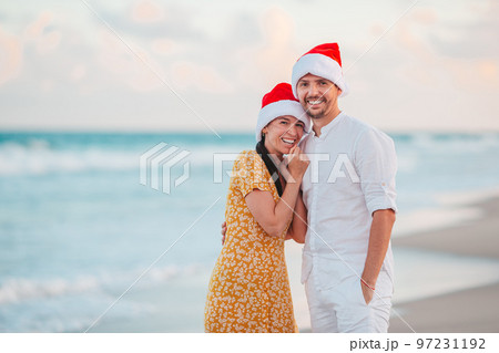 Christmas happy couple in Santa hats on beach vacation 97231192
