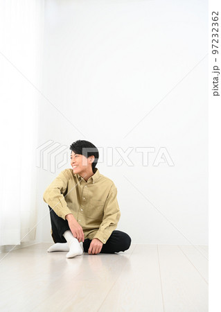 部屋で床に座る男性 97232362