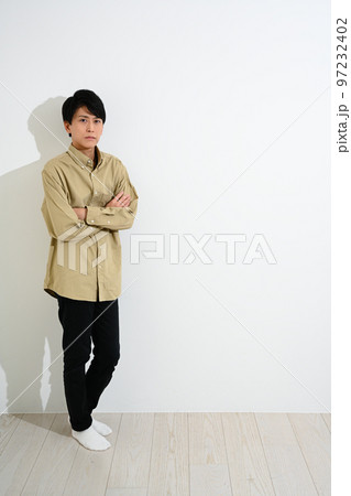 白い壁に寄りかかって立つ若い男性 白い壁に寄りかかって立つ若い男性 97232402