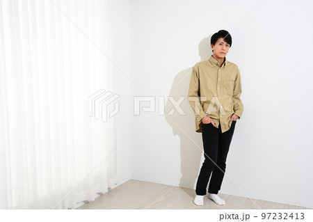 白い壁に寄りかかって立つ若い男性 97232413