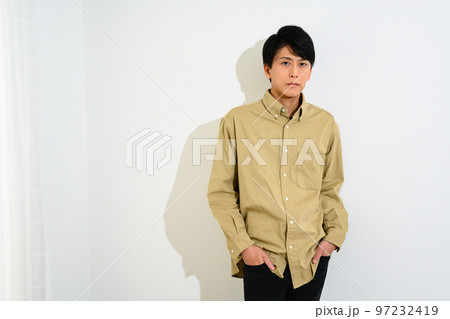 白い壁に寄りかかって立つ若い男性 97232419