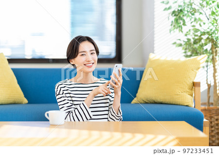 リビングでスマートフォンを操作する女性 リビングでスマートフォンを操作する女性 97233451