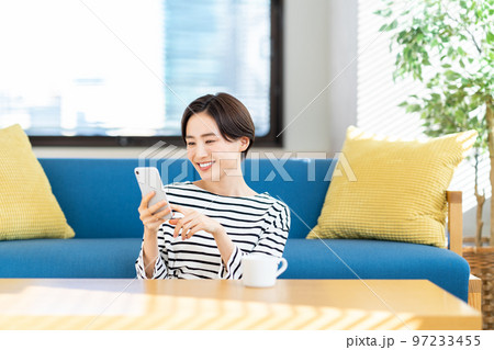 リビングでスマートフォンを操作する女性 97233455