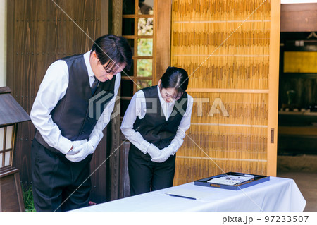 お葬式・告別式・お通夜の受付で挨拶するセレモニースタッフ・葬祭ディレクター・葬儀屋の男女 97233507