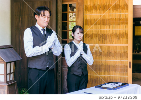 お葬式・告別式・お通夜の受付で挨拶するセレモニースタッフ・葬祭ディレクター・葬儀屋の男女 97233509
