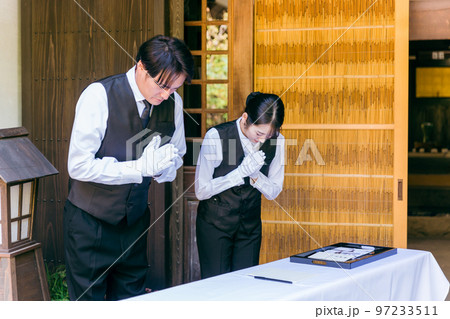 お葬式・告別式・お通夜の受付で挨拶するセレモニースタッフ・葬祭ディレクター・葬儀屋の男女 97233511