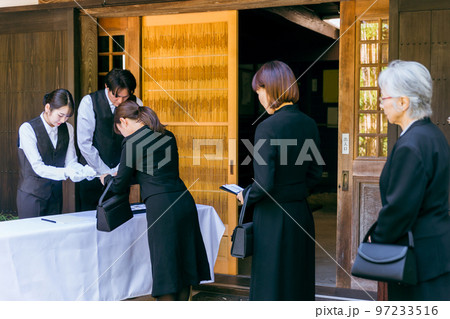 お葬式・告別式・お通夜の受付で香典を渡す遺族・弔問客と葬祭ディレクター 97233516