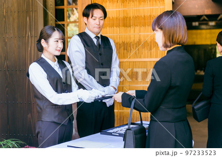お葬式・告別式・お通夜の受付で香典を受け取るセレモニースタッフ・葬祭ディレクターの男女 97233523