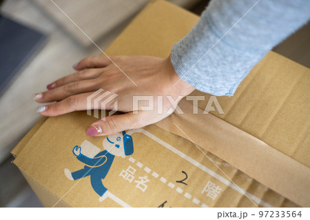引っ越しの荷造りをしている若い女性の手元 97233564