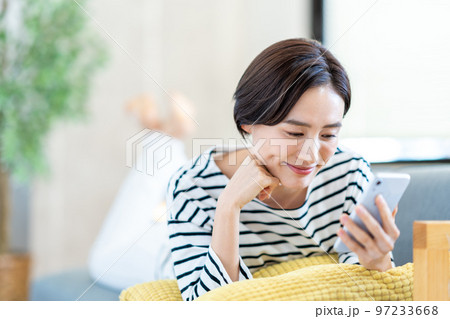 ソファーでスマートフォンを操作する女性 ソファーでスマートフォンを操作する女性 97233668