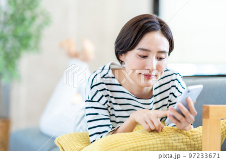 ソファーでスマートフォンを操作する女性 ソファーでスマートフォンを操作する女性 97233671