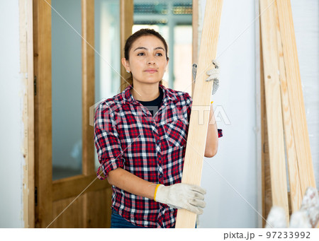 Woman carrying wooden planks during renovation works Woman carrying wooden planks during renovation works 97233992