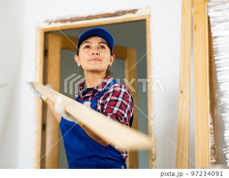Female worker installing door jambs in room being renovated Female worker installing door jambs in room being renovated 97234091