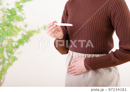 検査薬を見ながらお腹をさわる女性 検査薬を見ながらお腹をさわる女性 97234161