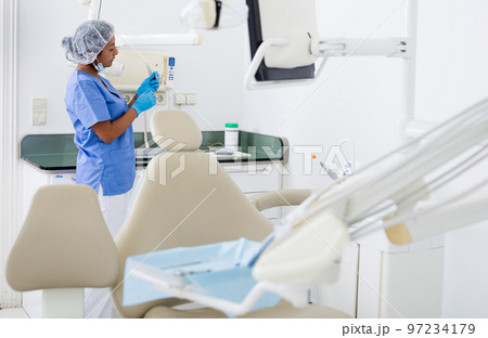 Female dentist checking and arranging tools in dental office 97234179