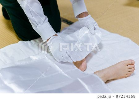 故人の死装束・脚絆をつける湯灌師・納棺師・おくりびと・エンバーマーの日本人女性（エンゼルケア・清拭） 97234369