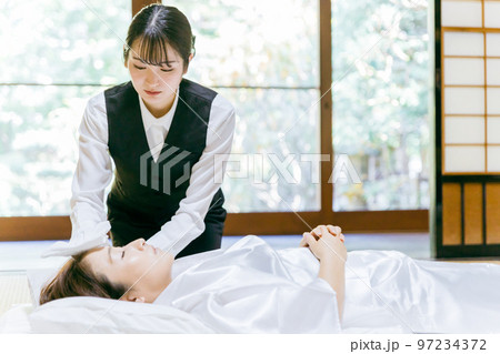 故人の体を拭く湯灌師・納棺師・おくりびと・エンバーマーの日本人女性（エンゼルケア・清拭） 97234372