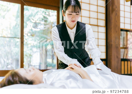 故人の手を組む湯灌師・納棺師・おくりびと・エンバーマーの日本人女性（エンゼルケア・清拭） 97234788
