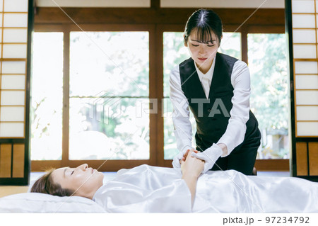故人の手を組む湯灌師・納棺師・おくりびと・エンバーマーの日本人女性（エンゼルケア・清拭） 97234792