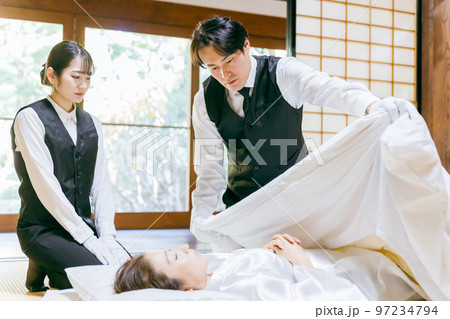 故人の手を組む湯灌師・納棺師・おくりびと・エンバーマーの日本人女性（エンゼルケア・清拭） 97234794