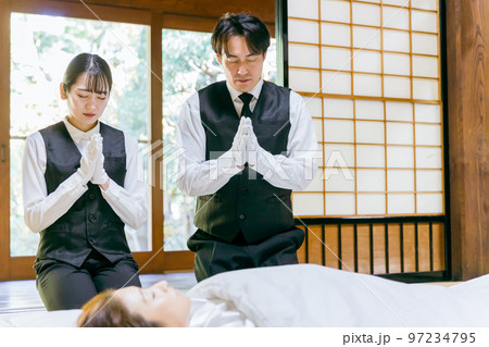 故人に手を合わせる湯灌師・納棺師・おくりびと・エンバーマー・セレモニースタッフの日本人男女 97234795