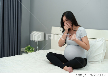 pregnant woman feeling nauseous on bed 97235149