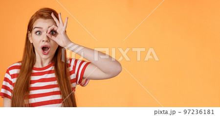 Surprised excited shocked young redhead girl gasping impressed look through okay circle, stare camera astonished awesome sale, open mouth say wow thrill and amazement, orange background Surprised excited shocked young redhead girl gasping impressed look through okay circle, stare camera astonished awesome sale, open mouth say wow thrill and amazement, orange background 97236181