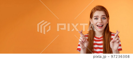 Excited hopeful redhead girl hope win lottery, smiling optimistic, look faith, believe dream come true, cross fingers good luck, make wish, anticipate good news, praying fortune, orange background Excited hopeful redhead girl hope win lottery, smiling optimistic, look faith, believe dream come true, cross fingers good luck, make wish, anticipate good news, praying fortune, orange background 97236308