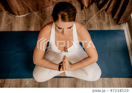 Well looking middle aged woman with long hair, fitness instructor in white sportswear, doing stretching and pilates on yoga mat at home. Healthy lifestyle, harmony, fitness yoga and meditation. Well looking middle aged woman with long hair, fitness instructor in white sportswear, doing stretching and pilates on yoga mat at home. Healthy lifestyle, harmony, fitness yoga and meditation. 97238520