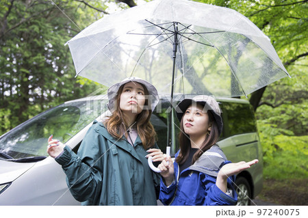 キャンプ場に到着して雨が降っていてがっかりする女性友達　アウトドアイメージ 97240075