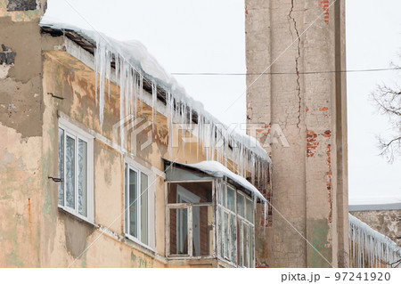 Icy, frozen icicles hang on the edge of the roof, spring or winter.  97241920