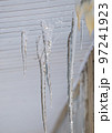 Multiple, melting icicles hanging through cracks, spring or winter.  97241923