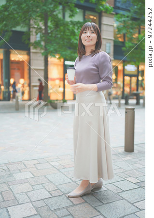 コーヒーカップを持って街を歩く女性 コーヒーカップを持って街を歩く女性 97244252