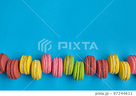 Colored macaron or macaroon, sweet meringue-based confection on blue background. Close-up, copy space. Colored macaron or macaroon, sweet meringue-based confection on blue background. Close-up, copy space. 97244611