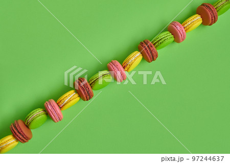 Colored macaron or macaroon, sweet meringue-based confection on green background. Close-up, copy space. Colored macaron or macaroon, sweet meringue-based confection on green background. Close-up, copy space. 97244637