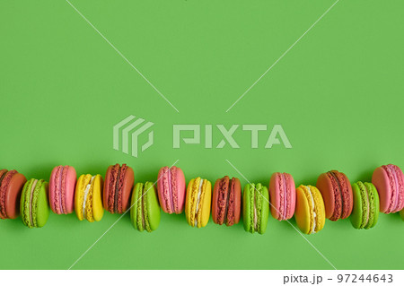 Colored macaron or macaroon, sweet meringue-based confection on green background. Close-up, copy space. Colored macaron or macaroon, sweet meringue-based confection on green background. Close-up, copy space. 97244643